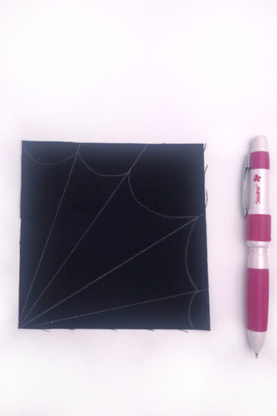 black fabric with a white spiderweb drawn on