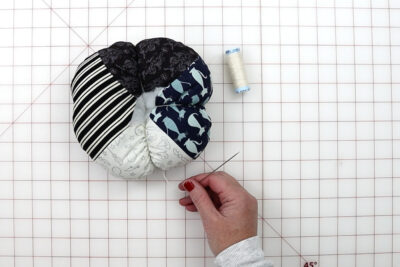 hands constructing fabric pumpkin with tools on white cutting mat