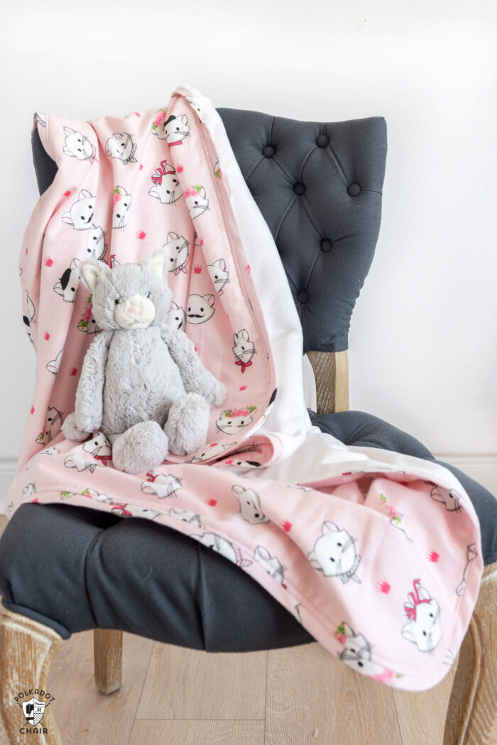 pink flannel blanket on gray chair with toy cat