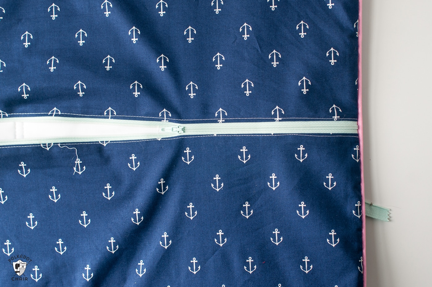 Back of navy pillow with pink piping, and aqua zipper