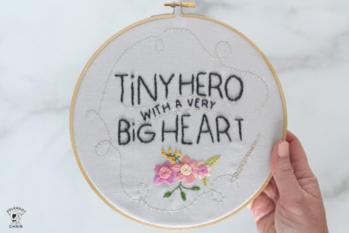 hand holding embroidery hoop with text