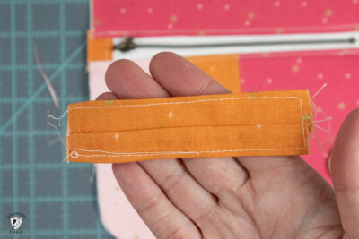 hand holding orange strip of fabric