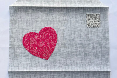 red heart and hand stitching on gray fabric