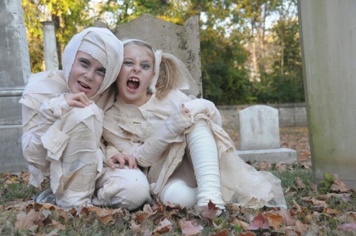 two kids in mummy costumes outdoors in the fall
