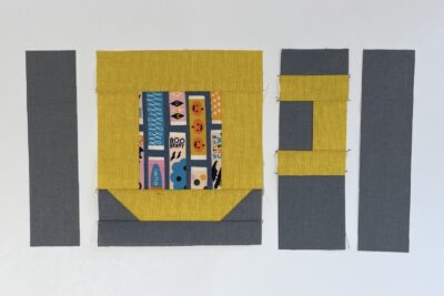 yellow cup quilt block with gray fabric on table