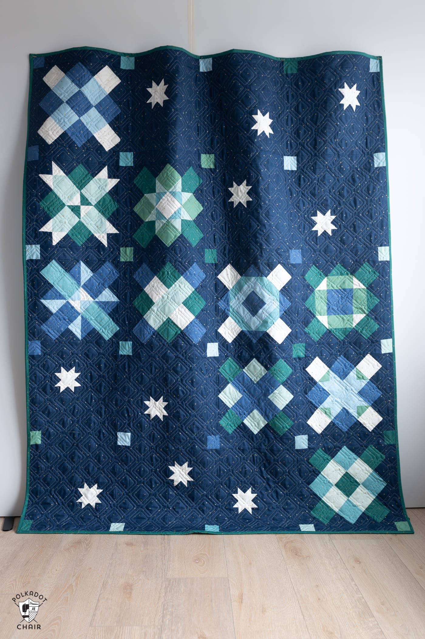 navy pieced quilt hanging on white wall