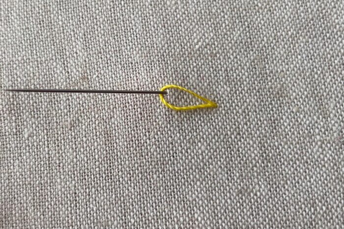 yellow embroidery thread on needle on canvas