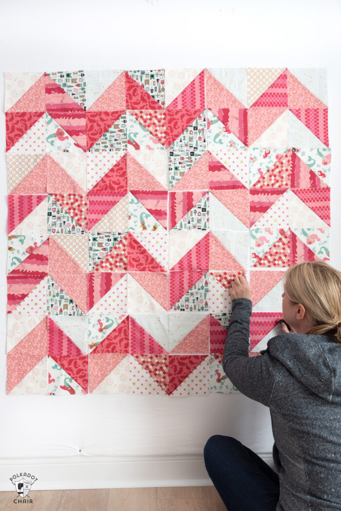 woman placing half square triangle quilt blocks on wall