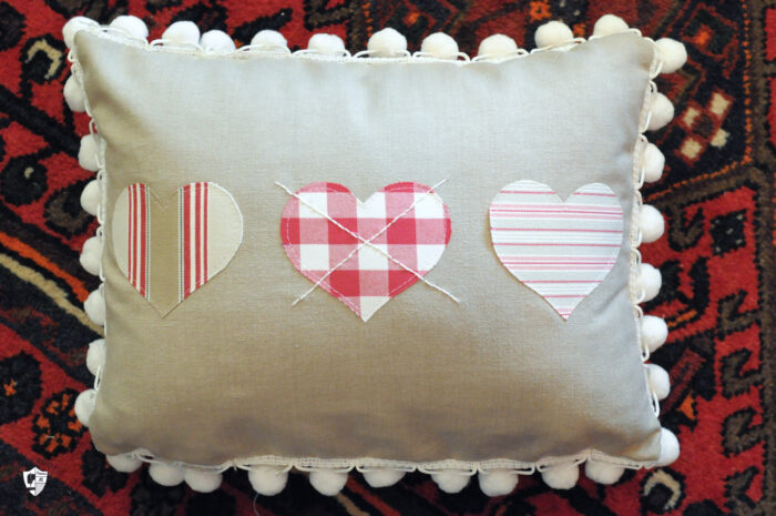 Linen colored heart pillow on red rug