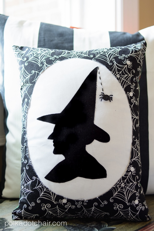 Black and white witch Halloween pillow in front of window